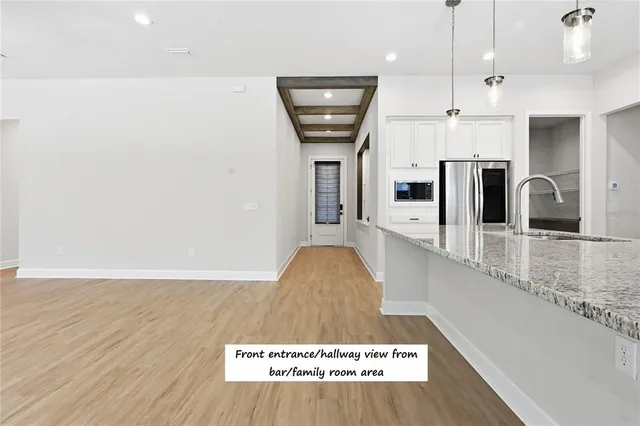 a view of a kitchen with stainless steel appliances granite countertop a sink a stove and a wooden floors