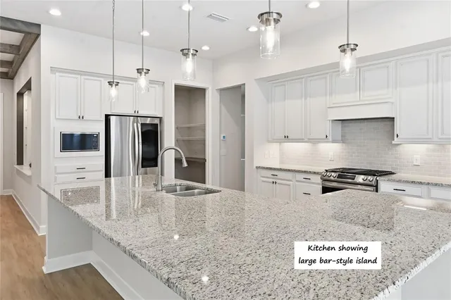 a large kitchen with stainless steel appliances granite countertop a sink a stove and a refrigerator