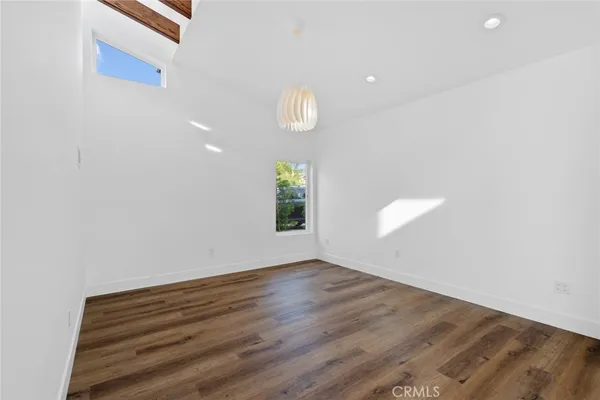 a view of an empty room with wooden floor and window