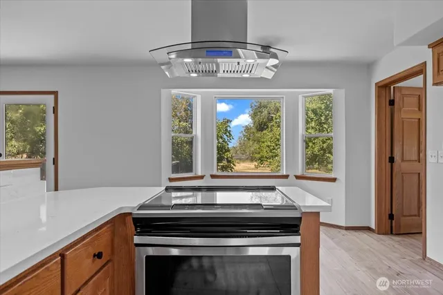 a view of a kitchen with a stove wooden floor and a hallway