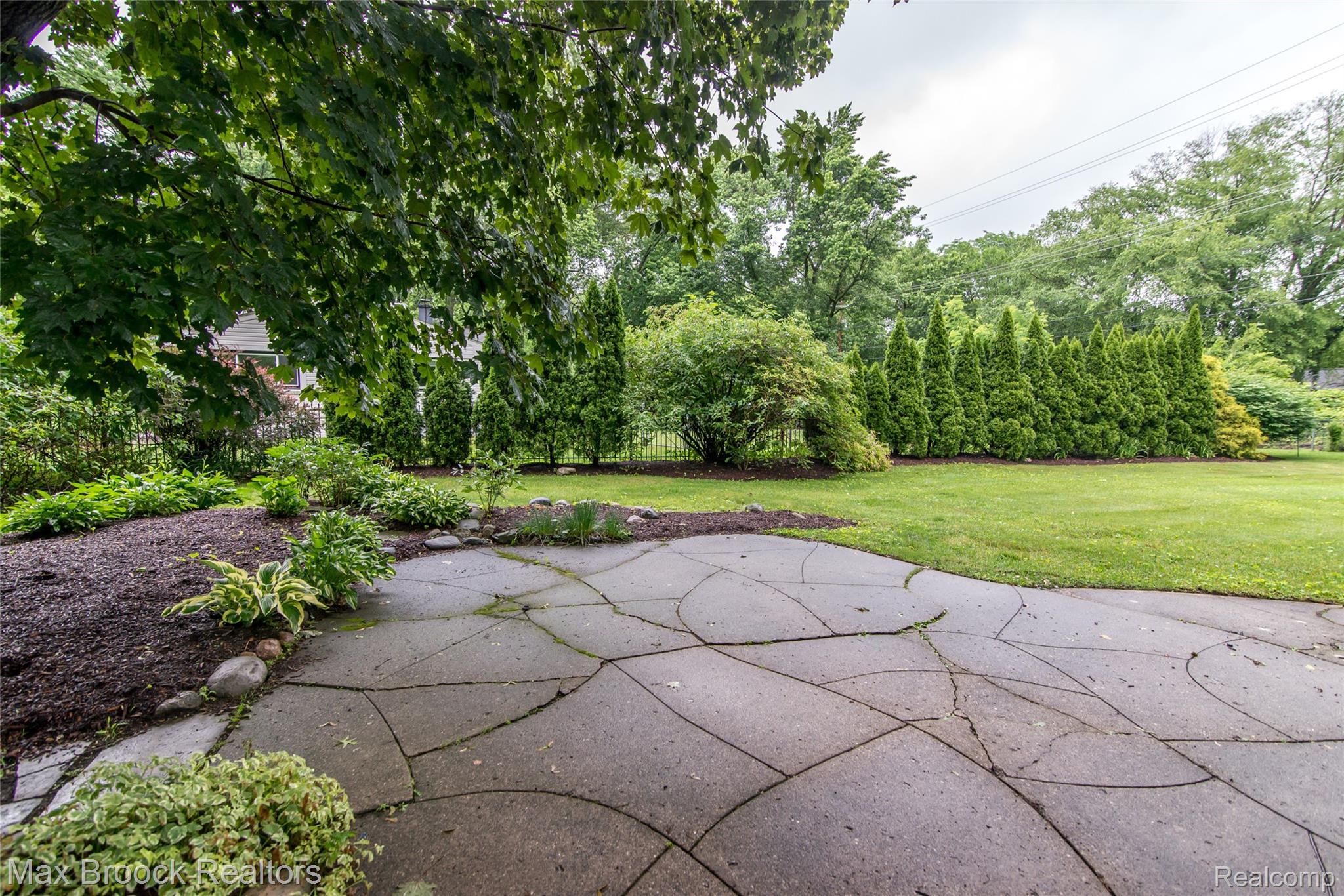 6799 East Dartmoor Road West Bloomfield, MI 48322 - Photo 28 of 36 Patio with irregular-cut stone pavers, surrounded by mulched garden beds and mature plantings