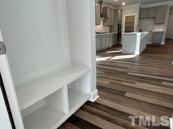 a view of kitchen and empty room with wooden floor