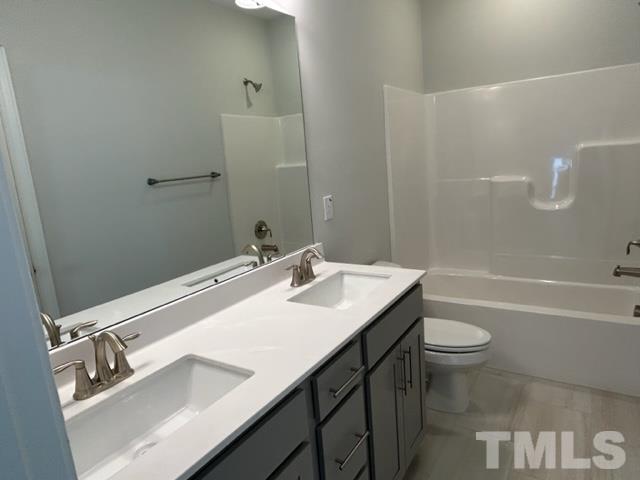 192 Edge Of Auburn Boulevard Raleigh, NC 27610 - Photo 24 of 44 a bathroom with a sink a toilet a mirror and shower