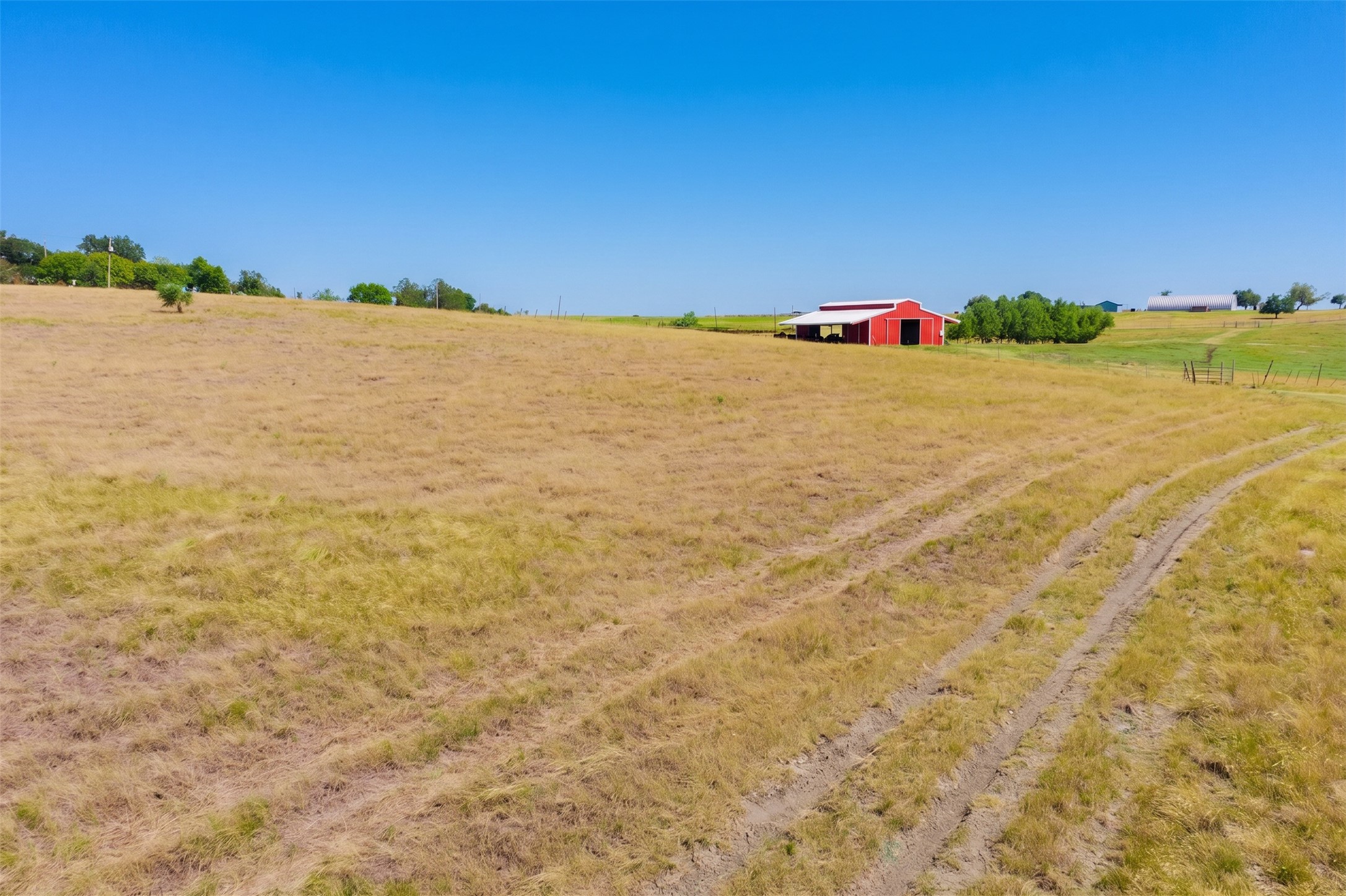 20145 Janak Road Coupland, TX 78615 - Photo 38 of 40 Acres of open pasture land with a classic red barn and distant hills.
