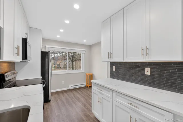 a kitchen with stainless steel appliances white cabinets and wooden floor