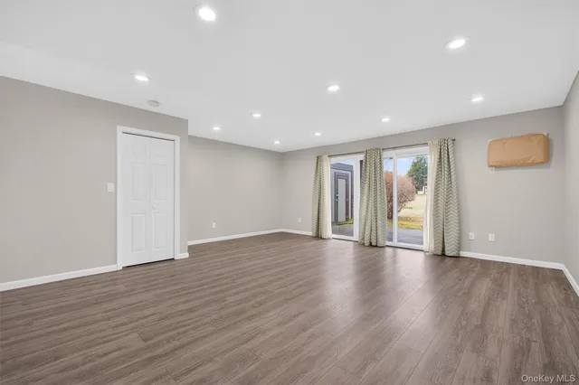 a view of an empty room with wooden floor and windows