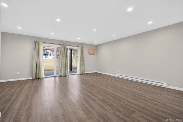 a view of an empty room with wooden floor and sliding door