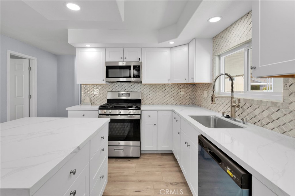 15252 Seneca Road, Unit 221 Victorville, CA 92392 - Photo 8 of 29 a kitchen with stainless steel appliances a sink dishwasher a stove top oven a refrigerator with white cabinets and wooden floor