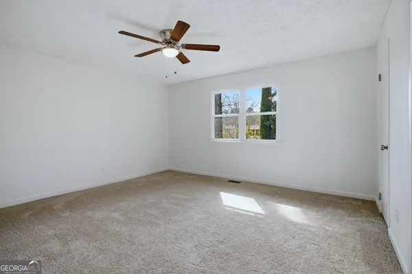 an empty room with a window and a ceiling fan