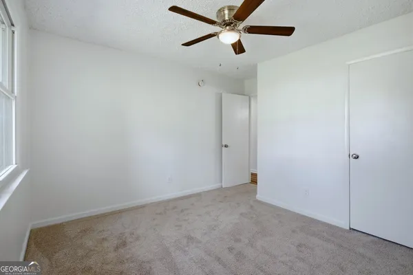 an empty room with a ceiling fan and a window