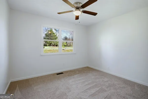an empty room with windows and fan