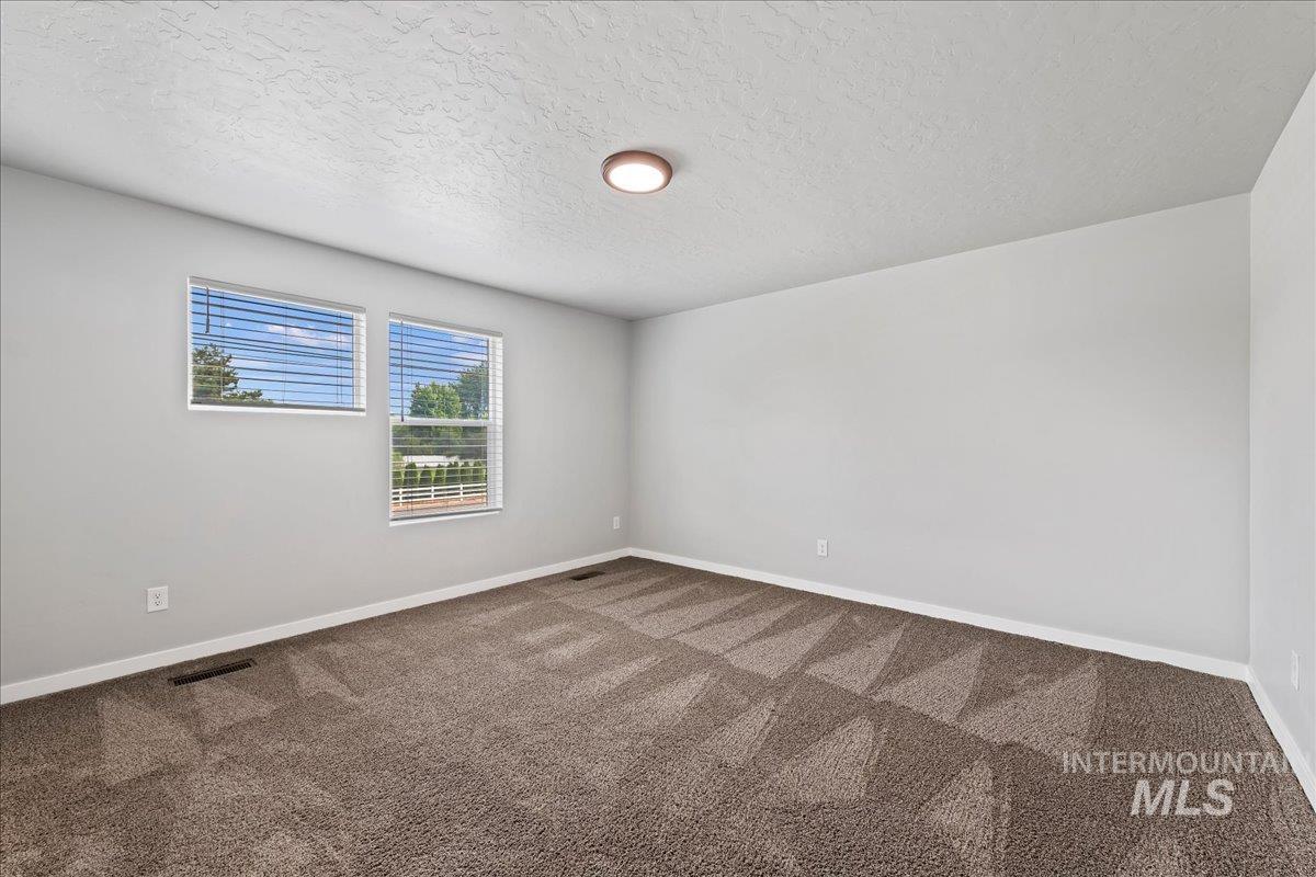 12535 West Victory Road Boise, ID 83709 - Photo 12 of 25 Neutral wall color, two windows with blinds, flush mount ceiling light, and patterned carpet