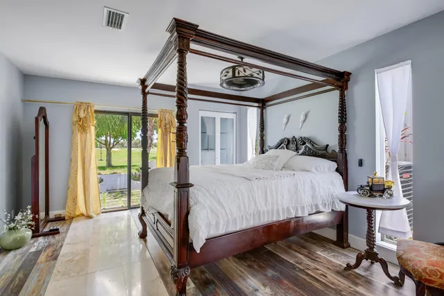 a bedroom with a bed a large window with table and chairs