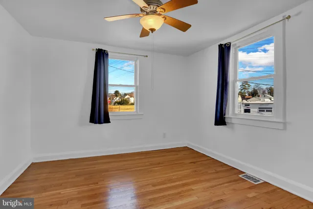 an empty room with wooden floor and ceiling fan