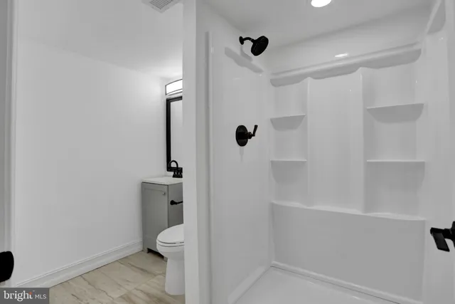 a view of a hallway with wooden floor and a bathroom