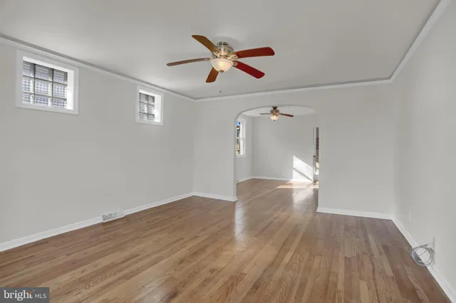 a view of empty room with wooden floor and ceiling fan