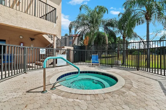 a view of a swimming pool with a couches chairs and wooden fence