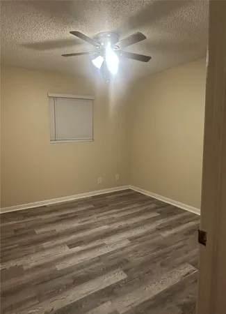 en empty room with wooden floor and fan