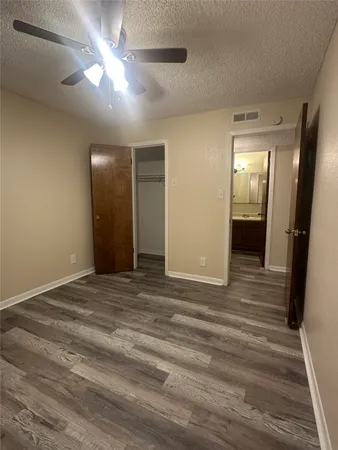 a view of an empty room with wooden floor and a ceiling fan