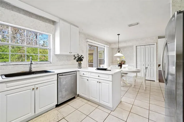 a kitchen with white cabinets and a window