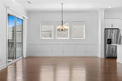 a view of an empty room with window wooden floor and kitchen view