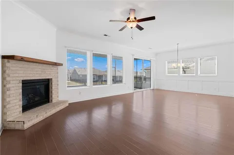 a view of an empty room with wooden floor fireplace and a window