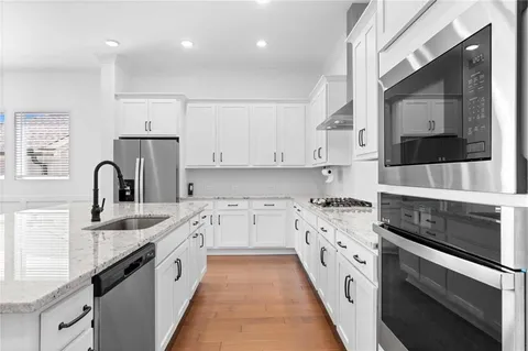 a large kitchen with stainless steel appliances granite countertop a sink and cabinets
