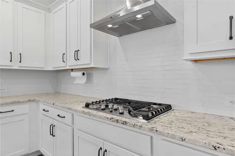 a kitchen with granite countertop white cabinets and stainless steel appliances