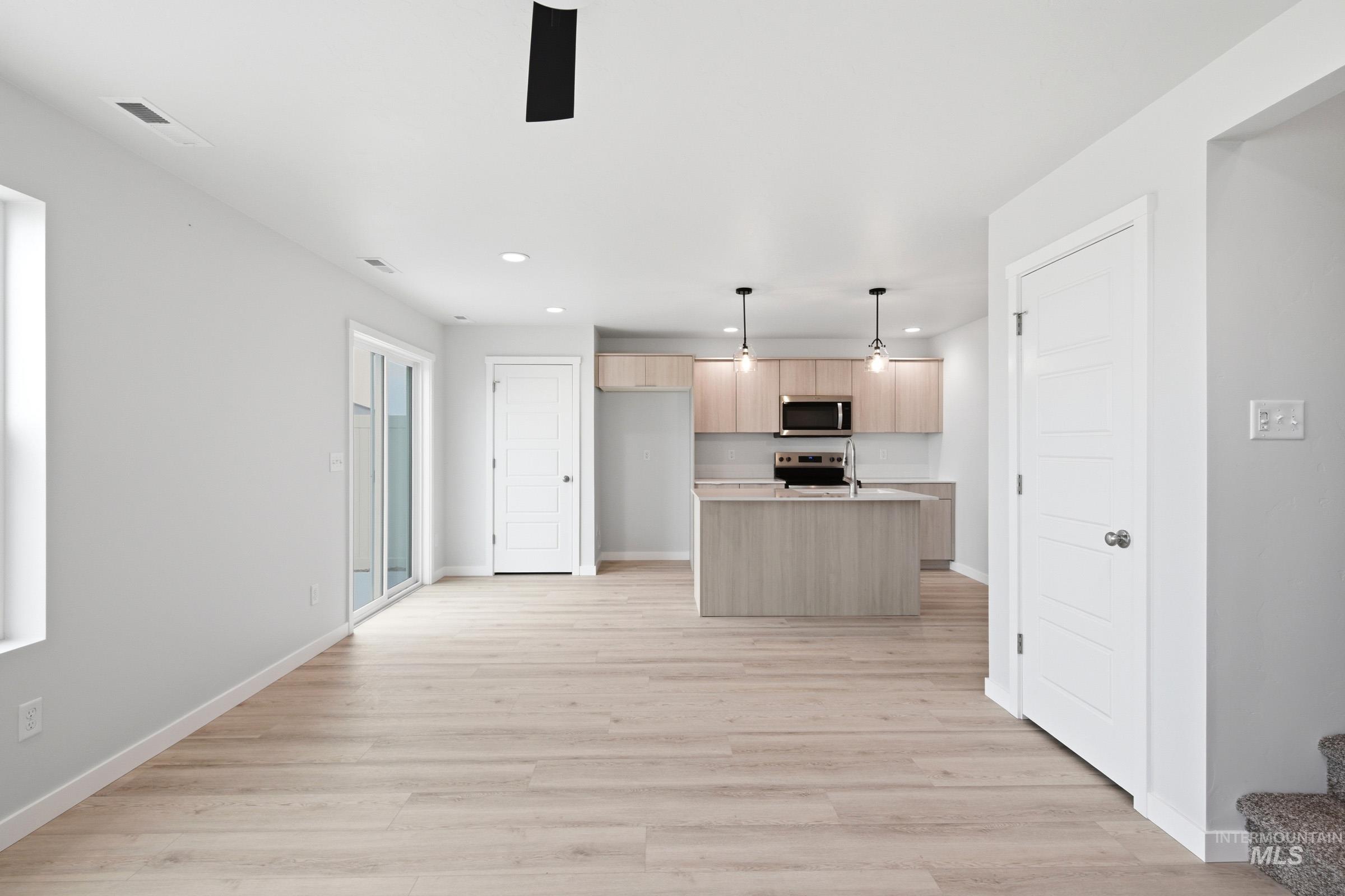 10788 Rutland Street Caldwell, ID 83605 - Photo 11 of 22 Kitchen featuring light wood finish cabinets, light countertops, decorative light fixtures, a center island with sink, and a ceiling fan