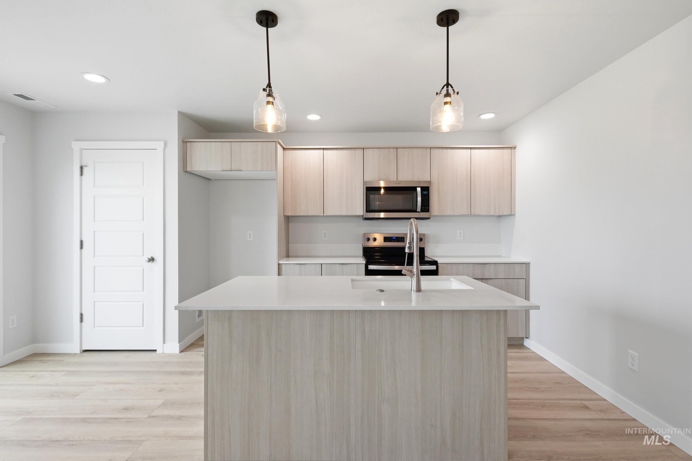 10788 Rutland Street Caldwell, ID 83605 - Photo 4 of 22 Kitchen with hanging light fixtures, light wood finish cabinetry, modern cabinets, and a kitchen island with sink