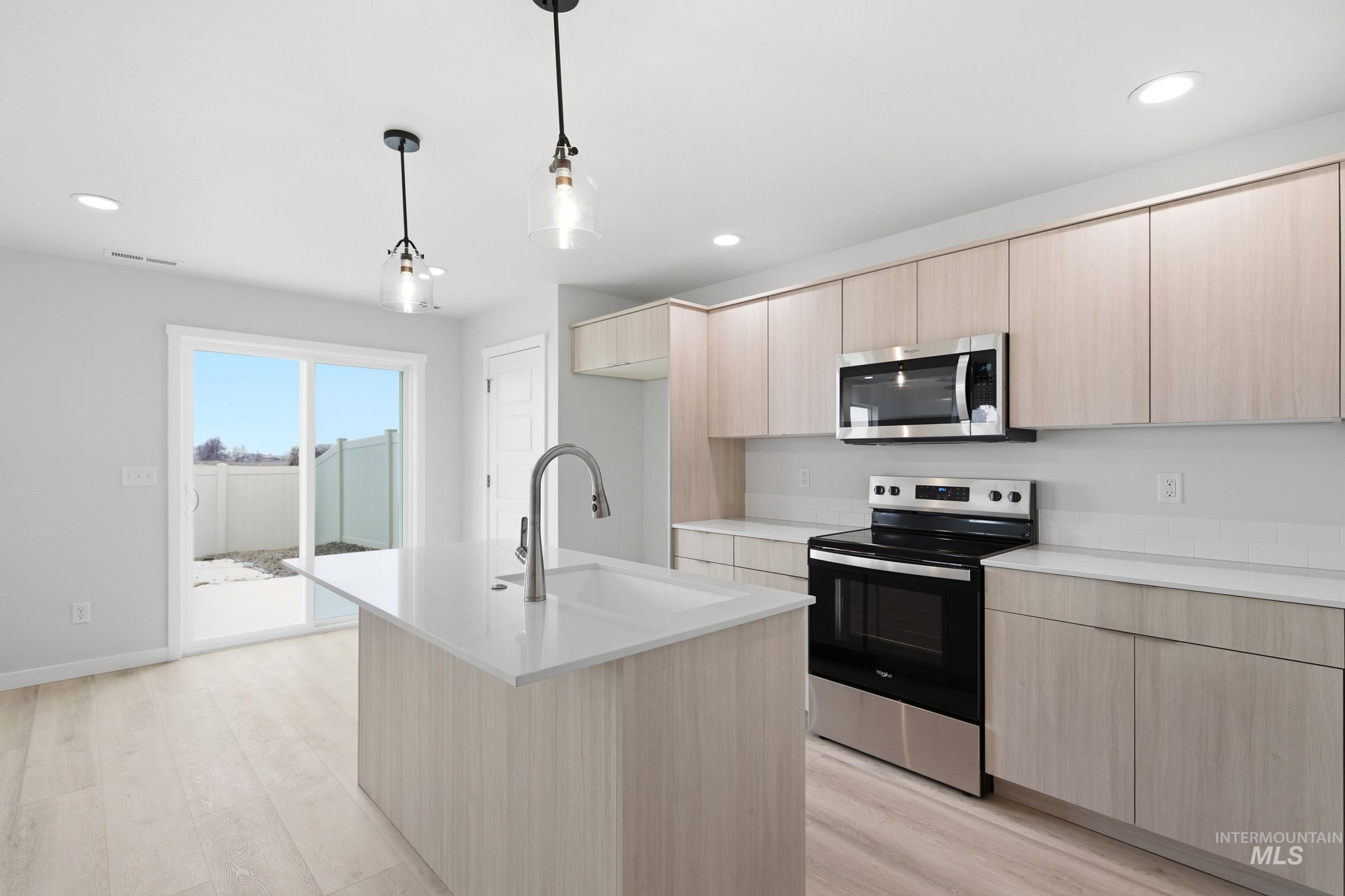 10788 Rutland Street Caldwell, ID 83605 - Photo 6 of 22 Kitchen featuring light wood finish cabinets, stainless steel appliances, pendant lighting, and a kitchen island with sink
