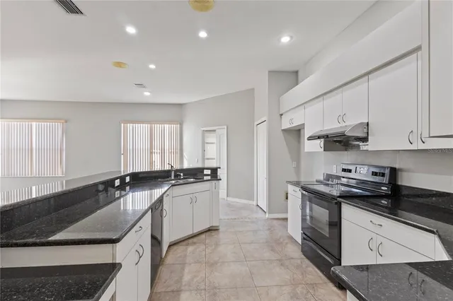 a kitchen with granite countertop a sink a stove and cabinets