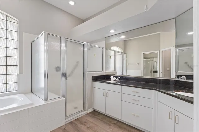 a spacious bathroom with a granite countertop sink mirror and a bathtub