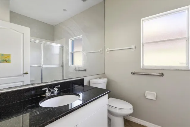 a bathroom with a granite countertop sink a large mirror and a toilet