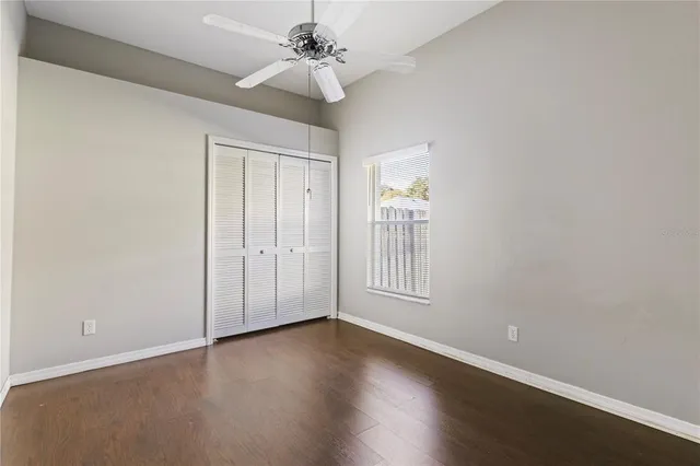 an empty room with wooden floor fan and windows