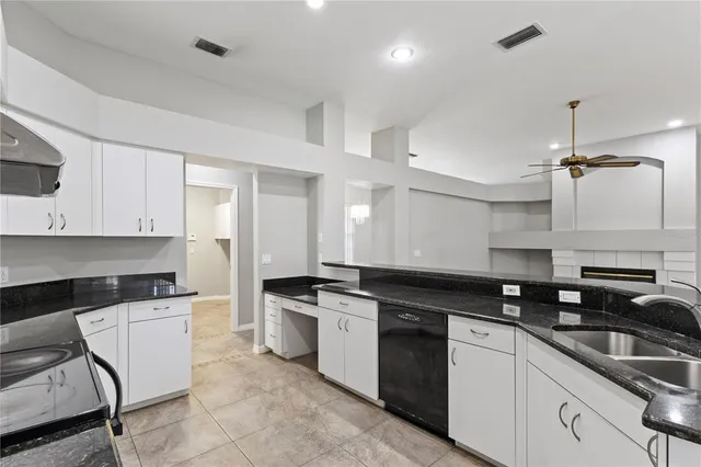 a kitchen with granite countertop a sink a stove and cabinets