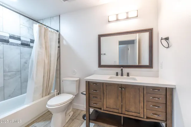 a bathroom with a toilet a sink a mirror a shower a vanity and window