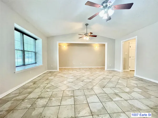 a view of an empty room and window and chandelier fan