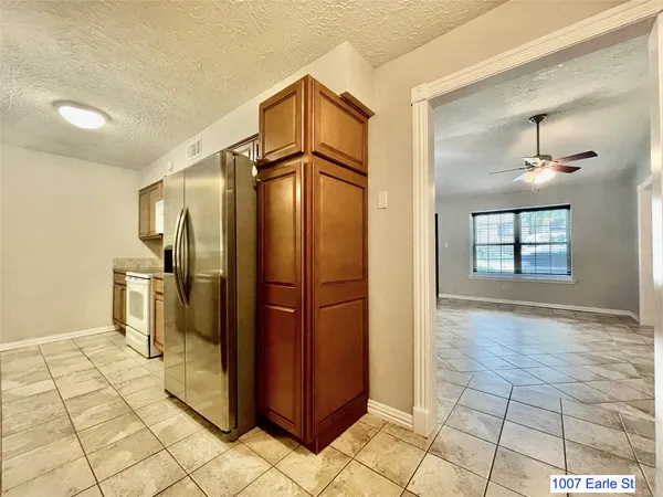 a view of a refrigerator in kitchen and an empty room