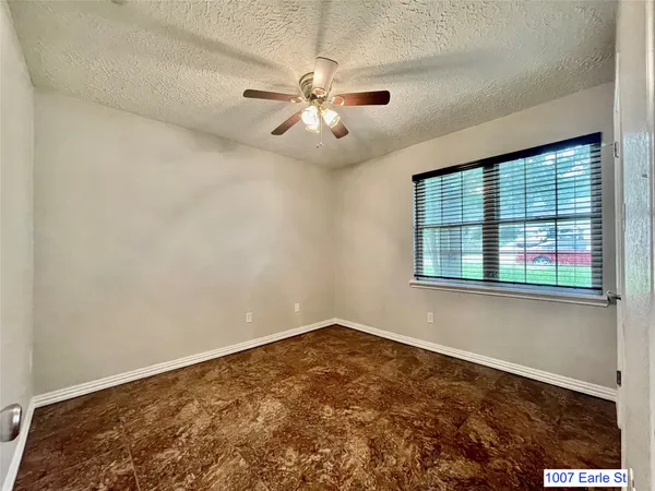 an empty room with windows and fan