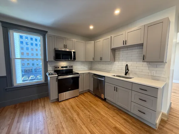 a kitchen with granite countertop a stove a sink and a refrigerator