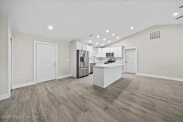 an empty room with wooden floor chandelier and windows