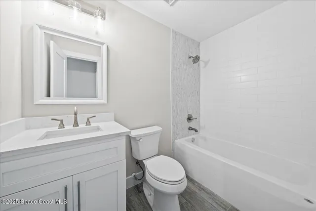 an empty room with wooden floor a ceiling fan and entryway