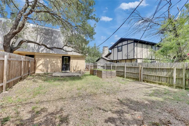 a view of a house with a yard and wooden fence