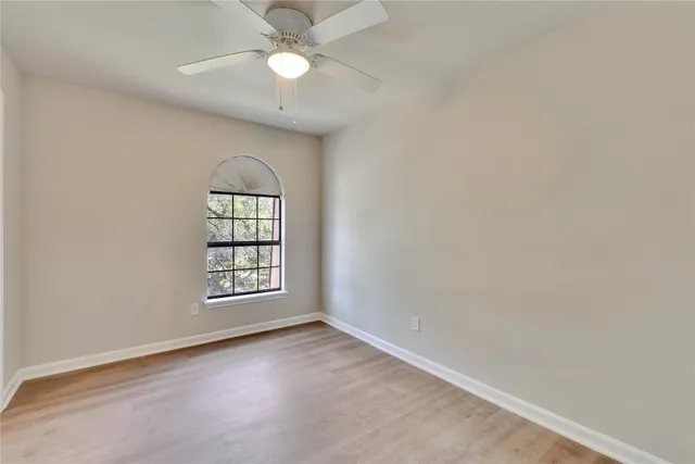 an empty room with windows and ceiling fan