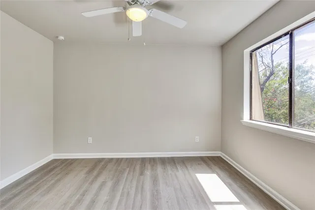 a view of empty room with wooden floor and fan