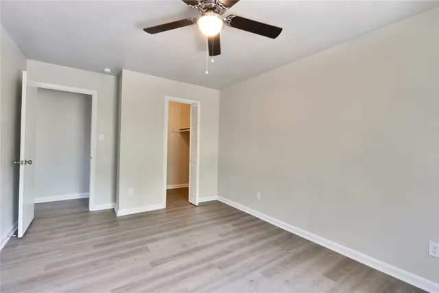 an empty room with wooden floor and ceiling fan
