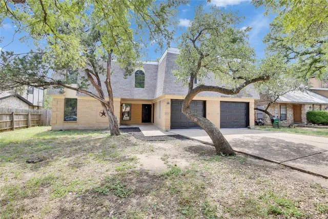 a view of a house with a yard and large tree