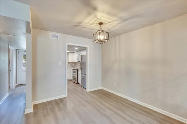 a view of a hallway with wooden floor and a chandelier