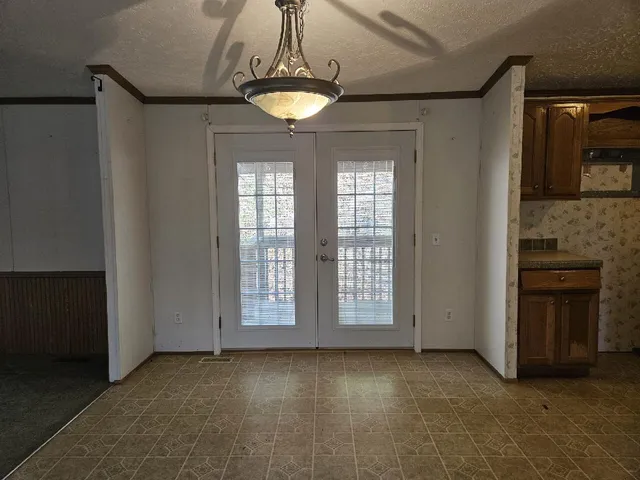 an empty room with chandelier fan and windows